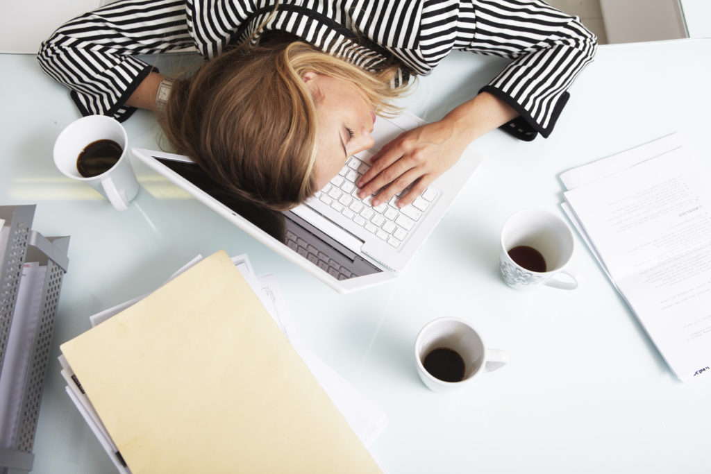 person asleep at desk reading a lease.